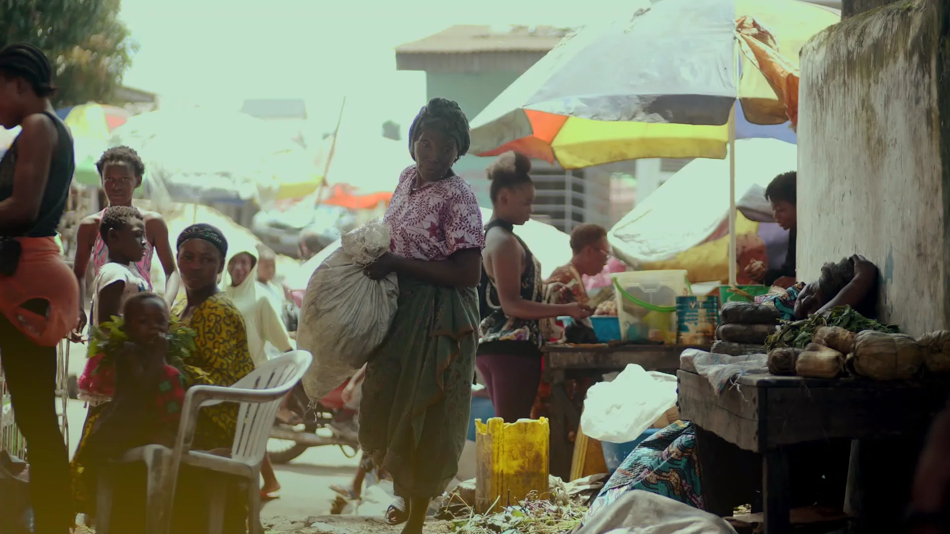 Maman Kungu traverse le marché, un sac sur la hanche, sous les parasols